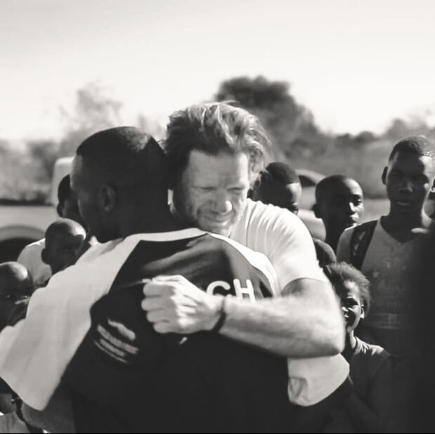 This image is of Matt Bracken and Orlando “Watch” Cossa. Matt and Watch embraced their shared situation for the first time in August 2016 in Corumana, Mozambique. Watch loves soccer and Matt loves the African Rhino, together they started a life long journey to uplift real communities to save people and rhinos. Image was extracted from video footage taken by Rohan Nel in August 2016.