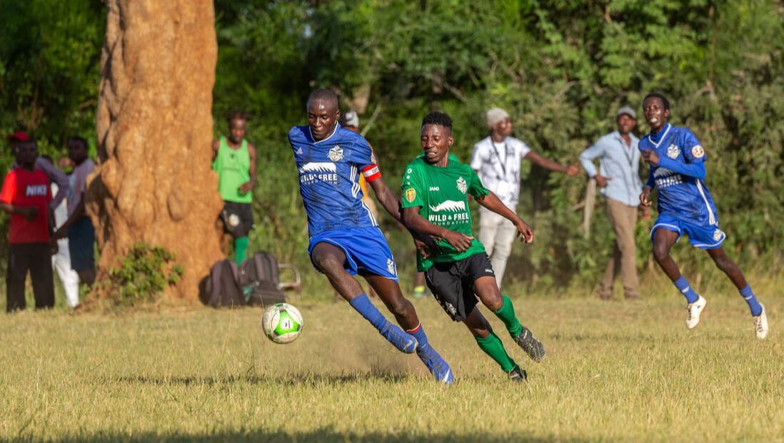 Two male football players engaged in a competitive match in Zimbabwe as part of the scheduled RCCL league during the beginning of the 2023 season. The blue football team is called Iwisa Sparrows FC. The football team known as Rock Rabbits FC is distinguished by its green color. They are proudly sponsored by Wild and Free Foundation. The RCCL Zimbabwe was launched in April, 2022.