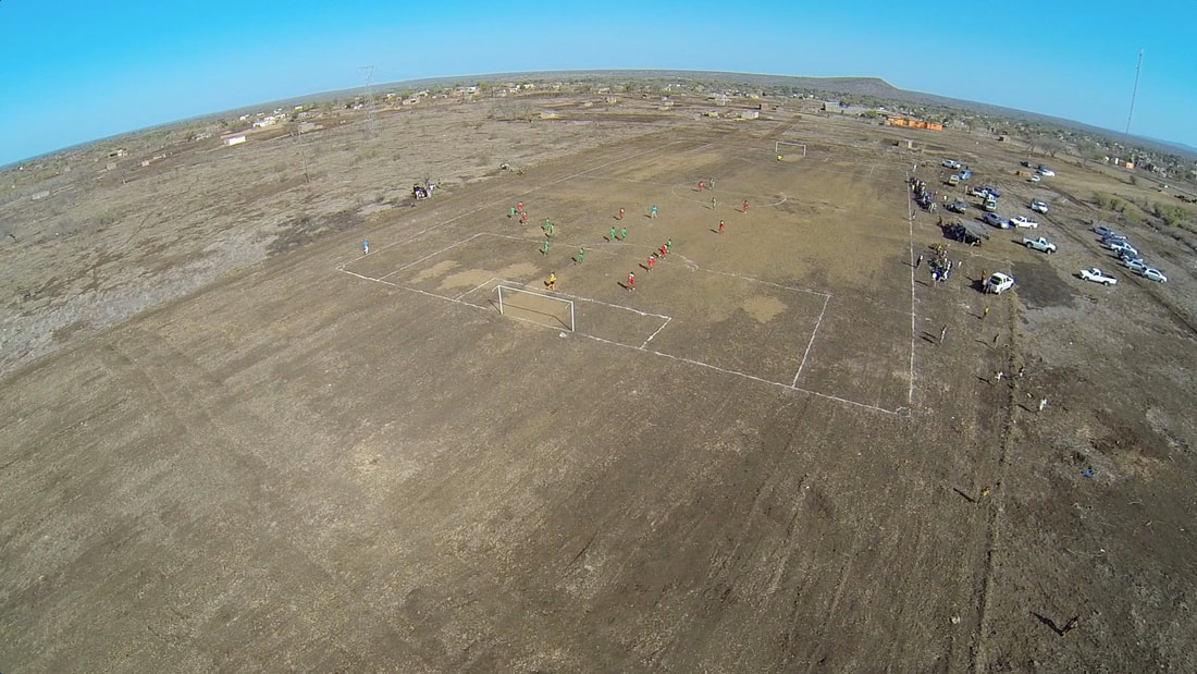 This is an overhead shot of the soccer pitch in Corumana in the early spring of 2016. This soccer match between Club de Corumana and Dakar FC is taking place on an extremely rocky field. Image that represents the start of the Rhino Cup journey.