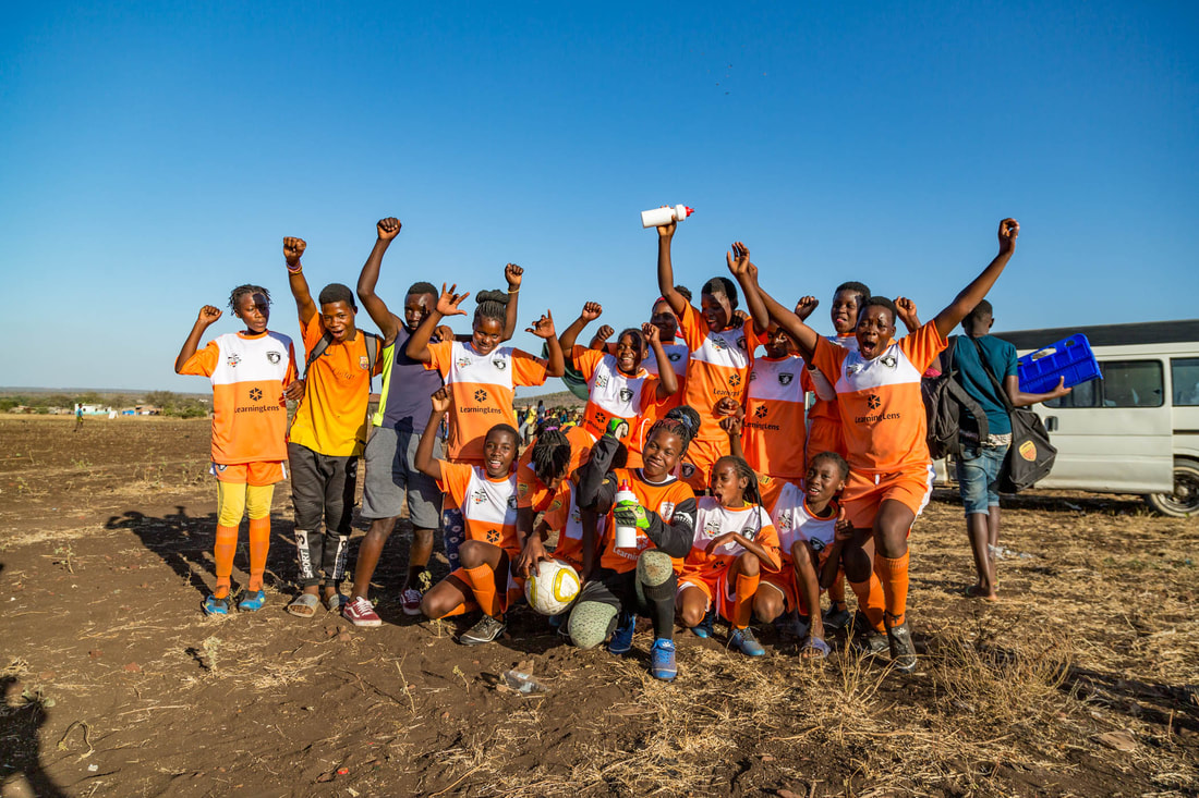 The female soccer team, Clube de Sabie F.C., posed for this photo after winning their very first game in the Women's Rhino Cup Champions League 2019. Clube de Sabie F.C. is sponsored by Learning Lens, Inc. (Business management consultant in Minneapolis, Minnesota).